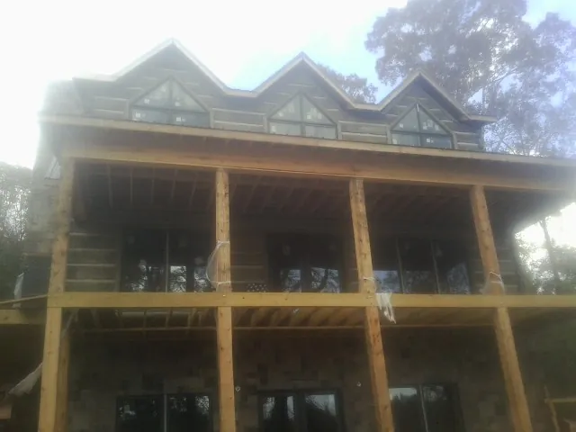 Dormers and porch framing on a large log home under construction — Roof Coating work by our crew in Corinth